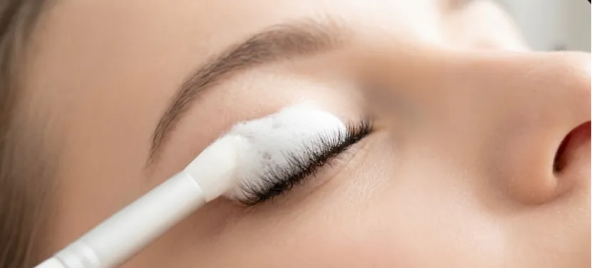 Applying gentle foam cleanser to eyelash extensions with a soft brush