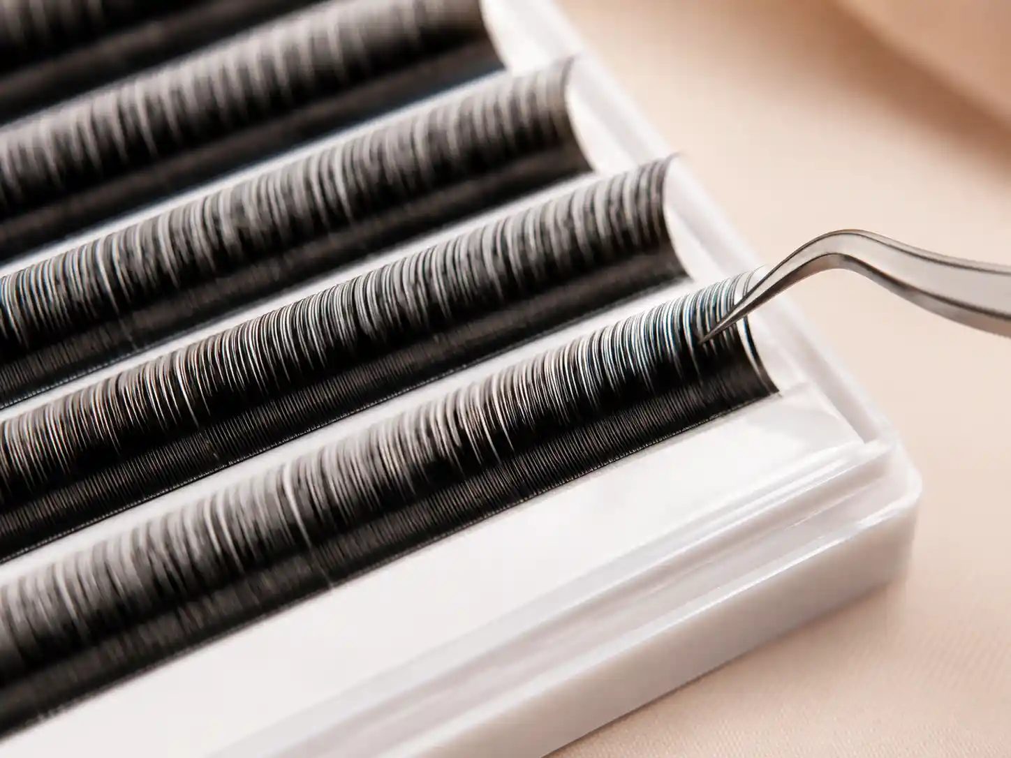 Tweezers picking lashes from an extension tray